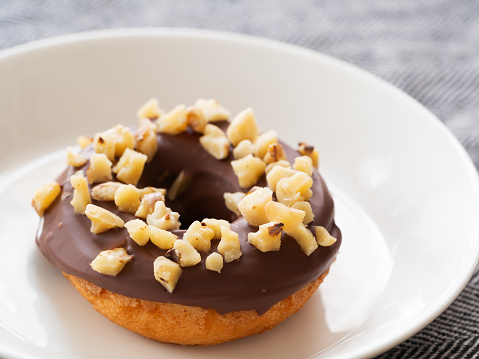 A donut with chocolate frosting and walnuts on top