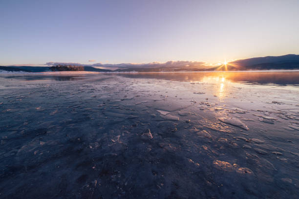 Frozen lake by sunset or sunrise in a cold winter morning or evening