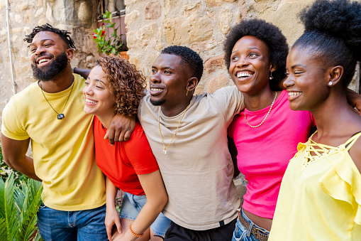 Young happy smiling multiracial group of people hugging together outdoors - Lifestyle concept with guys and girls having fun hanging out on park