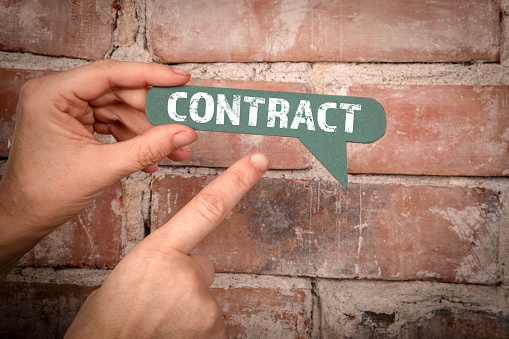 Contract. Green speech bubble with text on a red brick background.