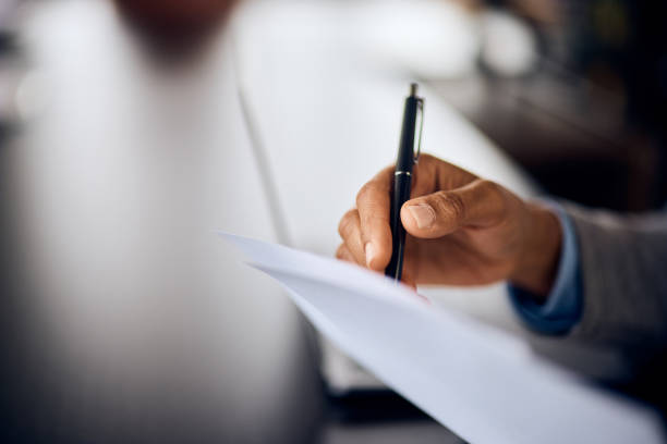 istock Close-up of a female hand, signing a document, using a pen. 1972246365