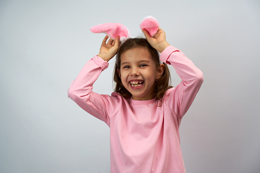 Funny happy child girl with Easter bunny ears on white background with copy space.