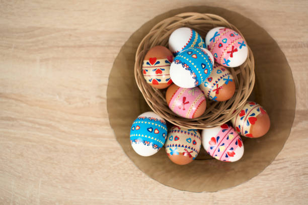 Easter basket with colorful Easter eggs on a wooden table background with copy space, close-up