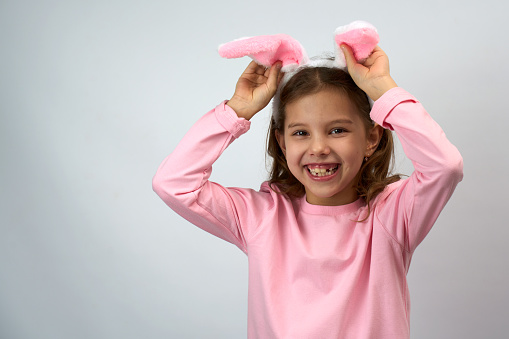 Funny happy child girl with Easter bunny ears on white background with copy space.