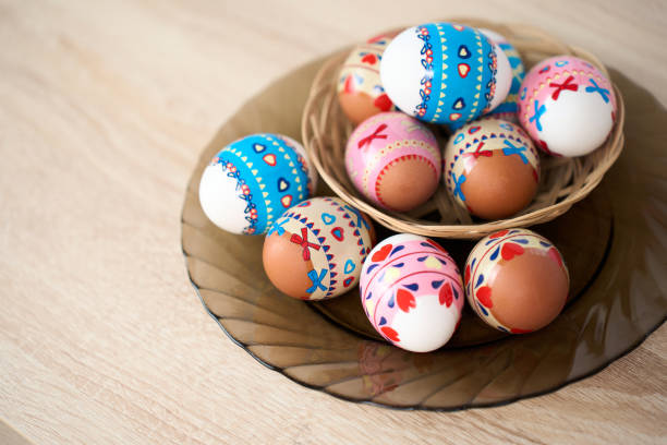 Easter basket with colorful Easter eggs on a wooden table background with copy space, close-up