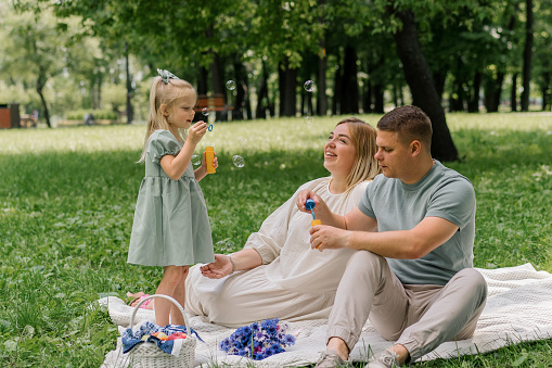 happy family relaxing outdoors in the park dad and daughter blowing soap bubbles Fun carefree childhood family weekend