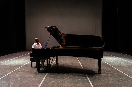 Mid adult man playing piano on stage teather