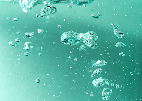 Detail of soap bubbles in clear blue liquid background