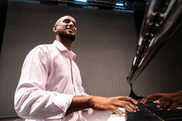 istock Mid adult man playing piano on stage teather 1972305143