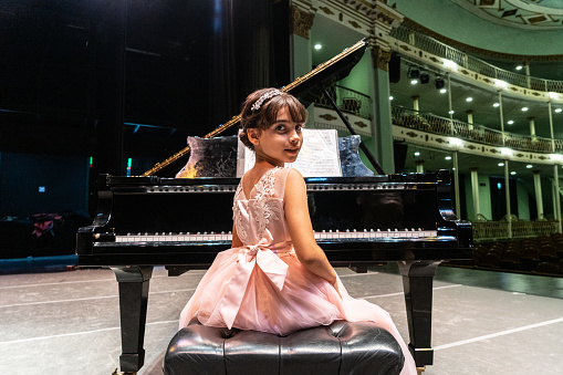Portrait of a child girl playing piano at stage theater