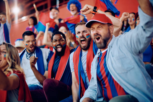 istock Passionate sports fans cheering while watching a game at the stadium. 1972318571