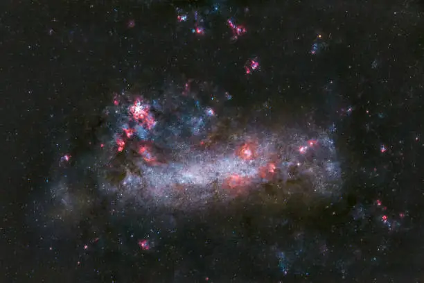 Photo of Astrophotography image of the Large Magellanic cloud, or nearest Galaxy with many stars and nebula, in glowing red hydrogen gas and blue oxygen gas, taken with a telescope