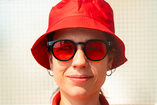Stylish young woman smiling and looking at camera with glasses and red hat.rait of a beautiful caucasian woman wearing red hat and glasses smiling looking at camera.