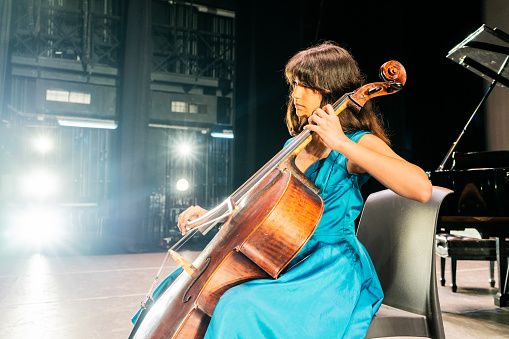Child girl playing cello at stage theater