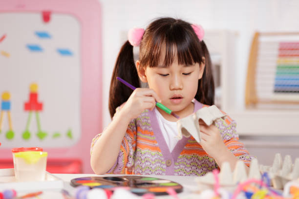 medium shot of young girl making craft at home