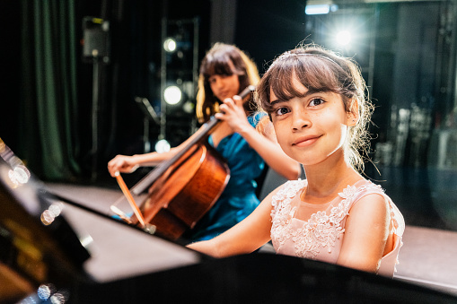 Portrait of a child girl playing piano at stage theater