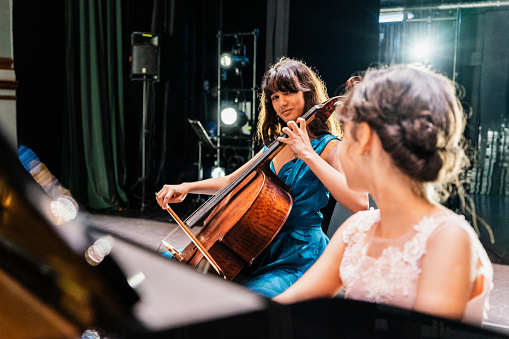 Sisters playing piano and cello at stage theater