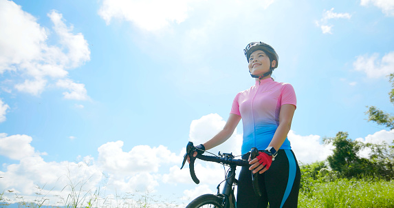 enjoy sport or healthy lifestyle concept -  asian young woman wearing helmet is ready to ride and standing by a bicycle on the road