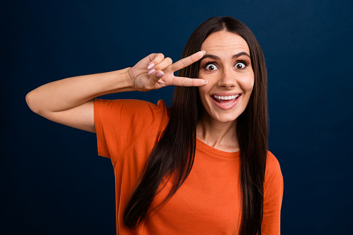 Portrait of funky cheeful nice good mood person wear stylish clothes showing v-sign on eye staring isolated on dark blue background.