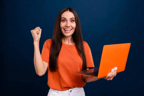 Photo of pretty lucky woman dressed orange t-shirt winning gale apple samsung modern device isolated dark blue color background.