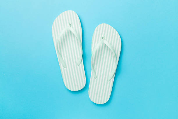 istock Striped flip flops on color background, top view 1972371831