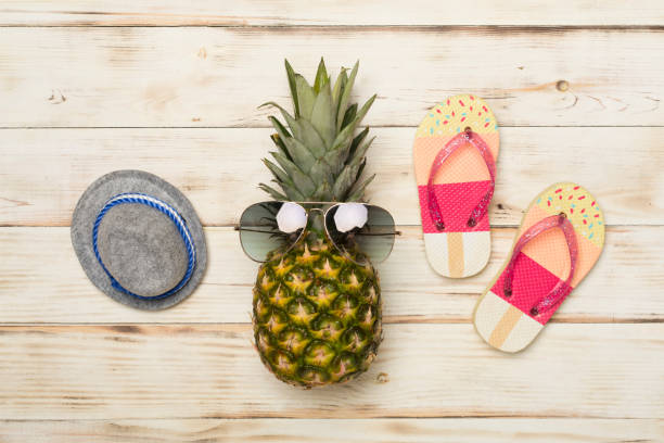 Creative pineapple hipster in sunglasses on color background, top view