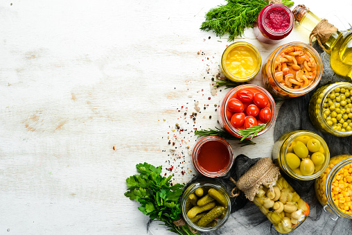 Background of food stocks in glass jars. Pickled vegetables and mushrooms. Top view.