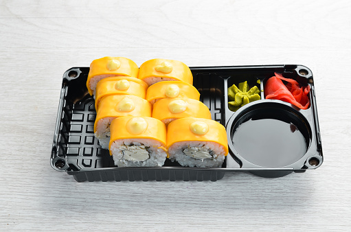 Delivery Japanese food. Sushi rolls with cheese, wasabi and soy sauce in a plastic box. Top view.