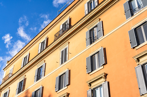 Shutters on the windows of a terracotta coloured apartment building in central Rome, Italy.