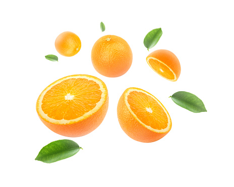 Orange fruit with cut half slice and green leaf flying in the air isolated on green color background.