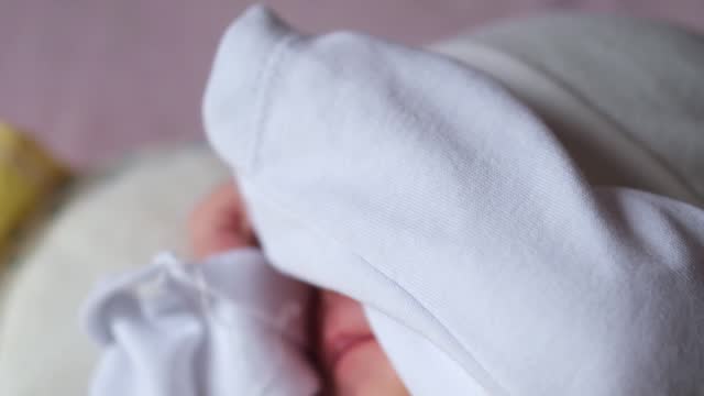 Newborn Baby sleeps sweetly on its side alone in parent's bed.