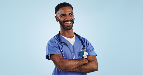 Happy man, portrait and professional doctor with arms crossed in medical care against a blue studio background. Male person, nurse or confident surgeon smile with stethoscope for healthcare on mockup