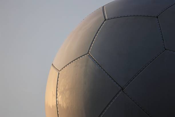 An elegant Abstract 3D Illustration of a spherical Structure intricately formed by interwoven, translucent Orange - Color (amber) strands. This Modern Design, reminiscent of a Celtic Knot or complex Weaving, symbolizes Connection, Complexity, and Cooperation. The glossy, Glass - Material like sphere, with its Glowing highlights and Reflections, floats against a serene Blue Background, suggesting themes of Innovation in Art or Technology. It's a beautiful Conceptual Symbol of unity and intricate Patterns.