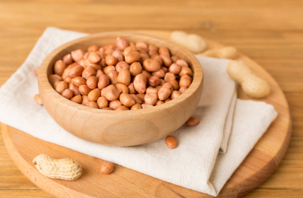 istock Peeled and unpeeled peanuts on wooden table 1972384238