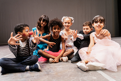 Portrait of children actors waving hands at stage theater