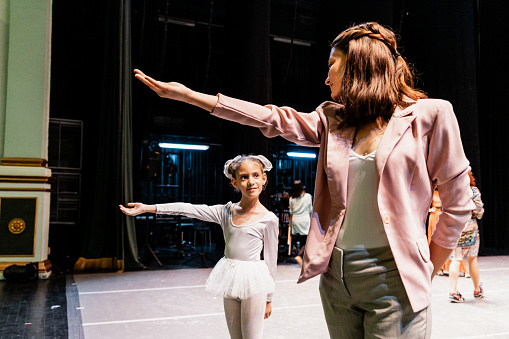 Child ballerina rehearsing with sister at stage theater