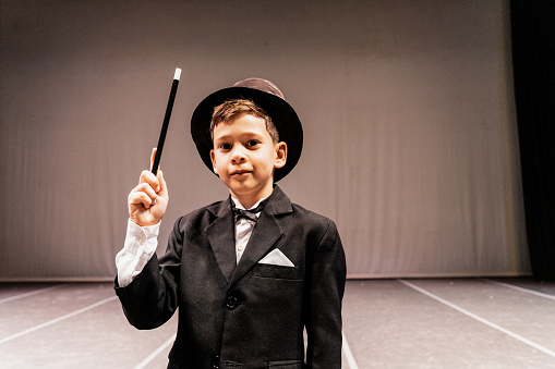 Portrait of a child magician boy on performance at stage theater