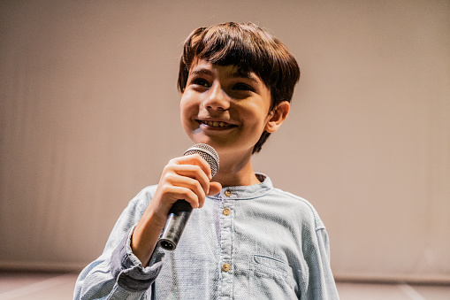 Child boy singing on performance at stage theater