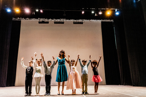 Portrait of children thanking the audience after performance at stage theater