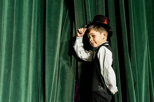 Portrait of child magician boy waiting to do a magic performance on the theater stage