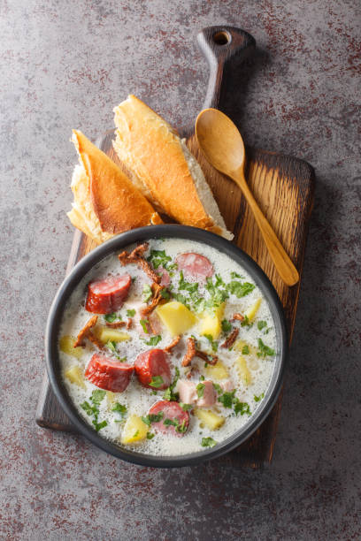 bortsch blanc polonais avec des légumes, des saucisses fumées, des champignons séchés et du bacon en gros plan dans une assiette. vue de dessus verticale - horseradish homemade eating food and drink photos et images de collection