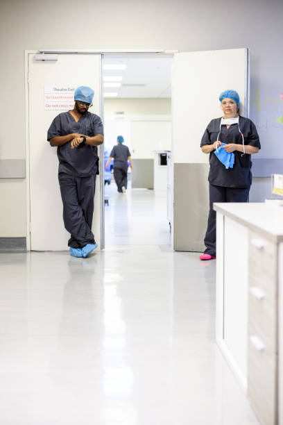 istock Nurses wearing scrubs wait holding doors open checking their watch waiting 1972411045