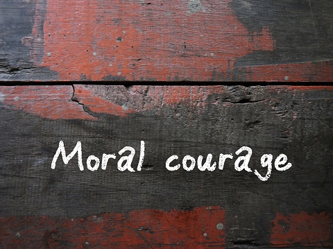 Grunge vintage wall with handwritten text MORAL COURAGE, means courage to take action for moral reasons or act upon ethical values to help others during difficult ethical dilemmas