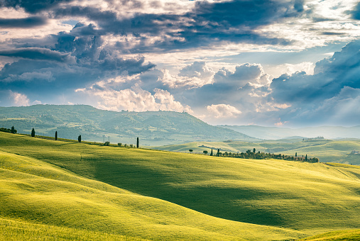 A sunbeam cuts through the rolling hills of Tuscany, illuminating the iconic landscape of Val d'Orcia, Italy, Europe.