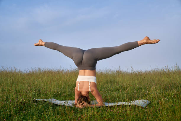 istock Fit woman stretching legs while standing on head outdoors 1972457651