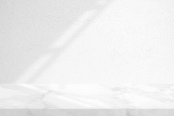istock Marble Table with White Stucco Wall Texture Background with Light Beam and Shadow of Roof, Suitable for Product Presentation Backdrop, Display, and Mock up. 1972463541