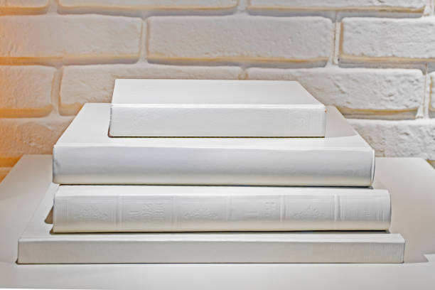 stack of white books on a white wall background. Education and
