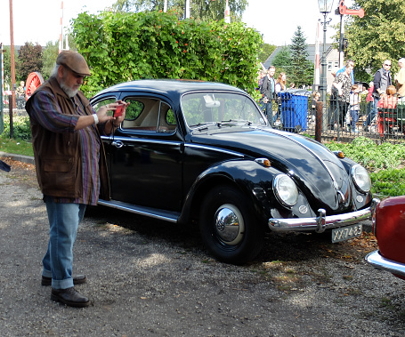 Loenen, Netherlands Sep 8 2019 A beautifully restored black Volkswagen Beetle with a photographing tourist in front