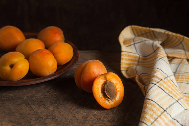 Whole and half of apricot fruits with clay plate with fruits on background. Composition on vintage wooden background.