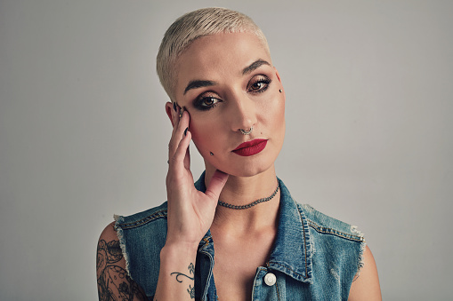 Punk, beauty and portrait of woman with makeup in studio on grey background or mock up. Serious, model and unique girl with glow on skin from cosmetics and cool trendy style with edgy aesthetic